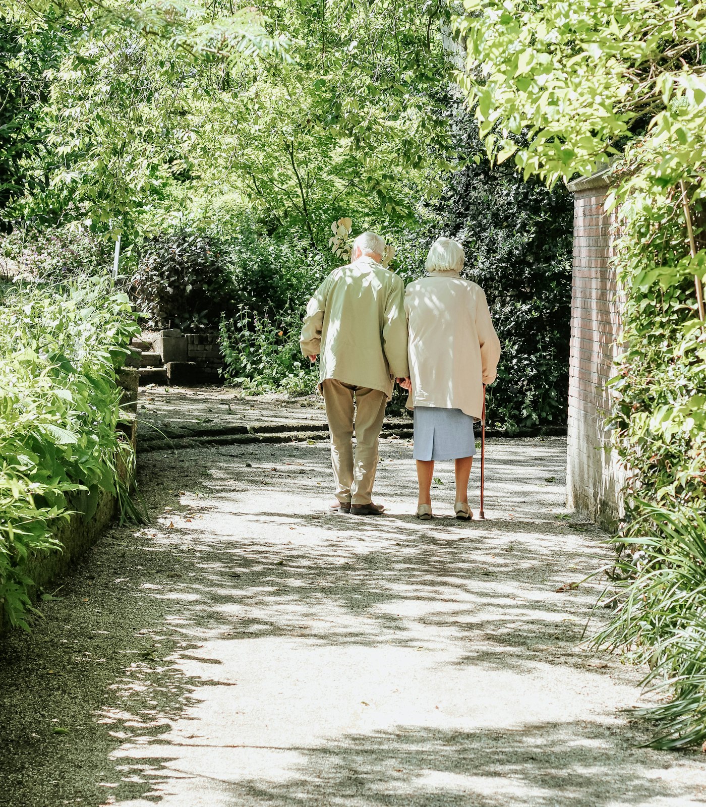 Pareja mayor paseando por un jardín soleado